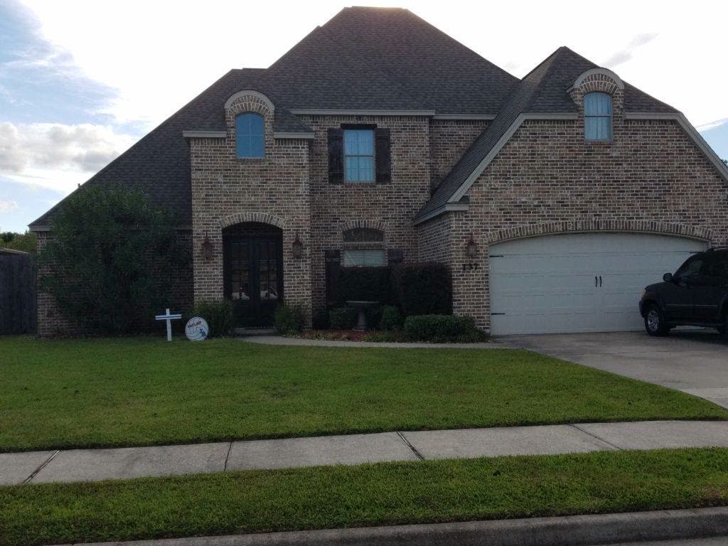 Brick two-story house with steep dark shingle roof and arched windows