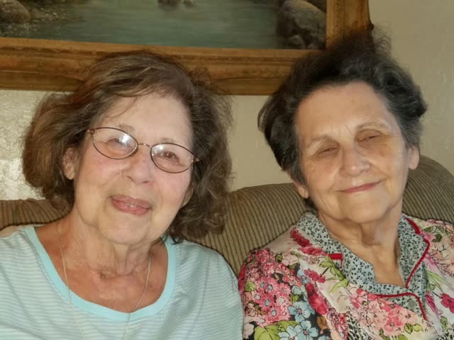 Two smiling older women sitting together, a Roofing 911 Program family