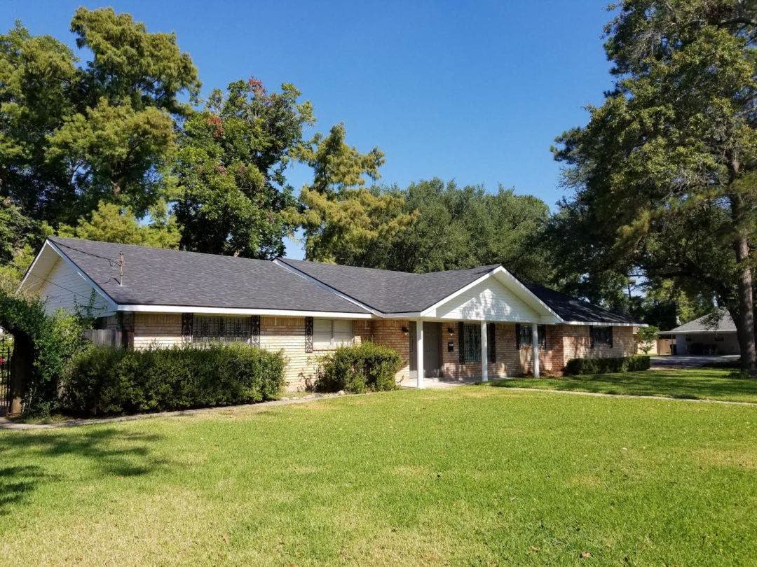 Long ranch house with a fresh grey shingle roof and a wide green lawn